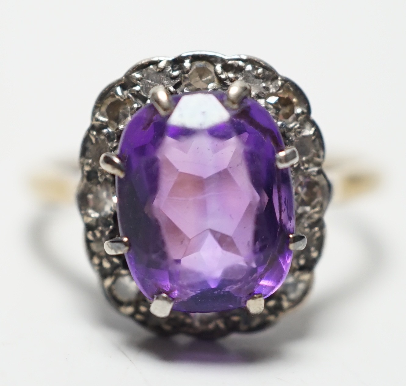 An 18ct, amethyst and diamond set oval cluster ring, size P, gross weight 4.5 grams.